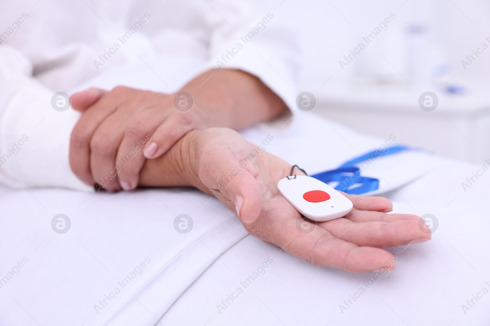 Photo of Senior woman with emergency call button on bed in hospital, closeup