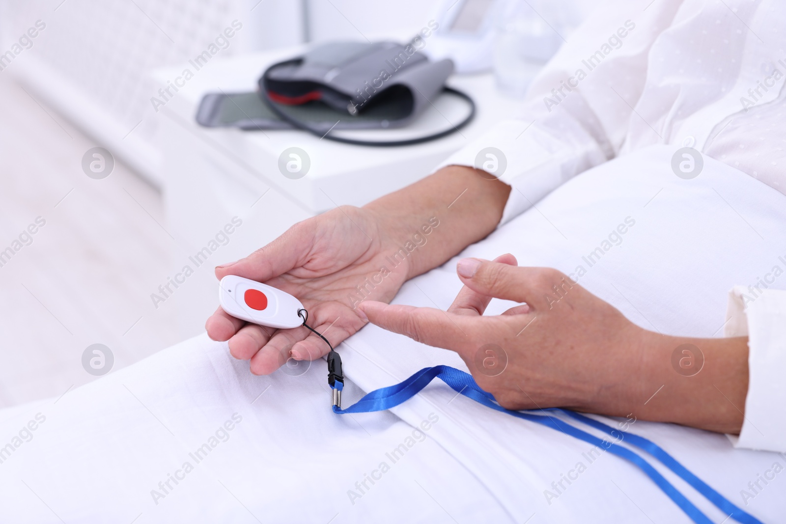 Photo of Senior woman with emergency call button on bed in hospital, closeup