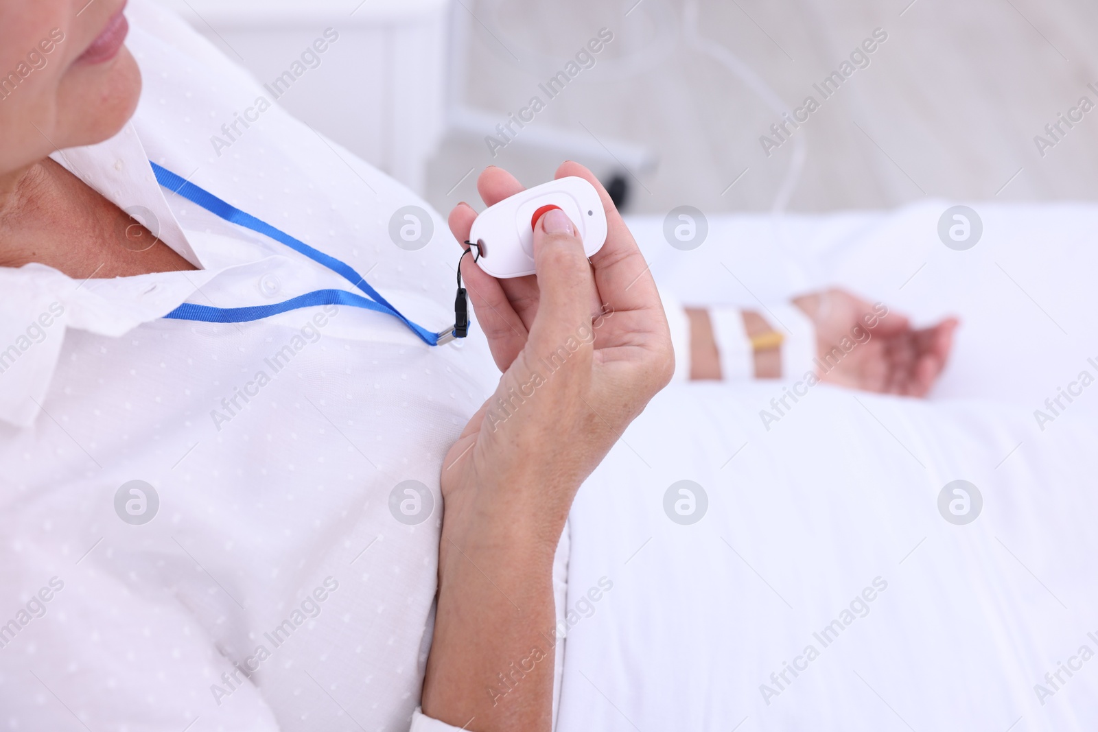 Photo of Senior woman pressing emergency call button on bed in hospital, closeup