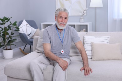 Senior man with emergency call button at home