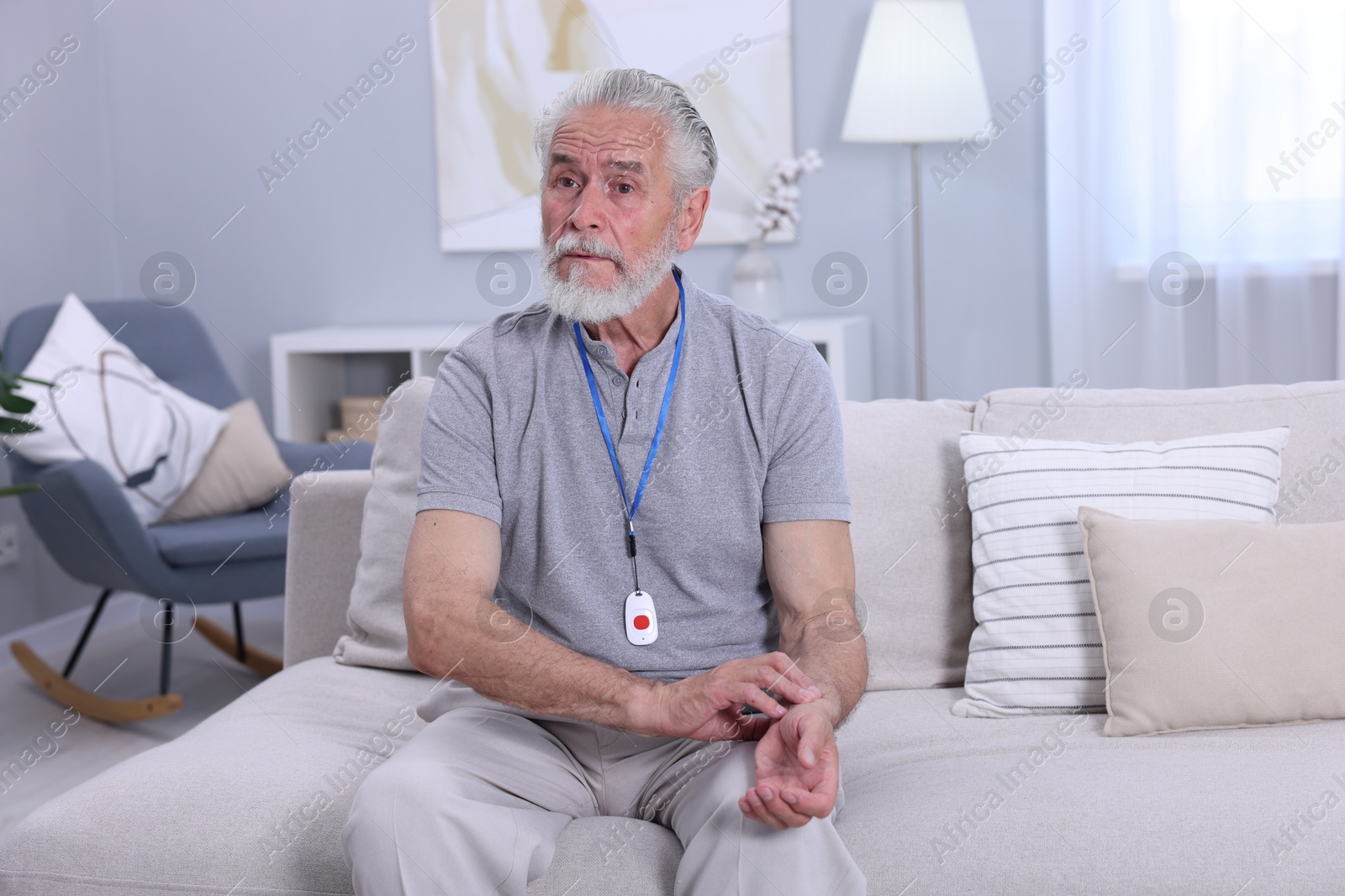 Photo of Senior man with emergency call button checking pulse on wrist at home