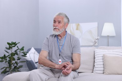 Senior man with emergency call button checking pulse on wrist at home