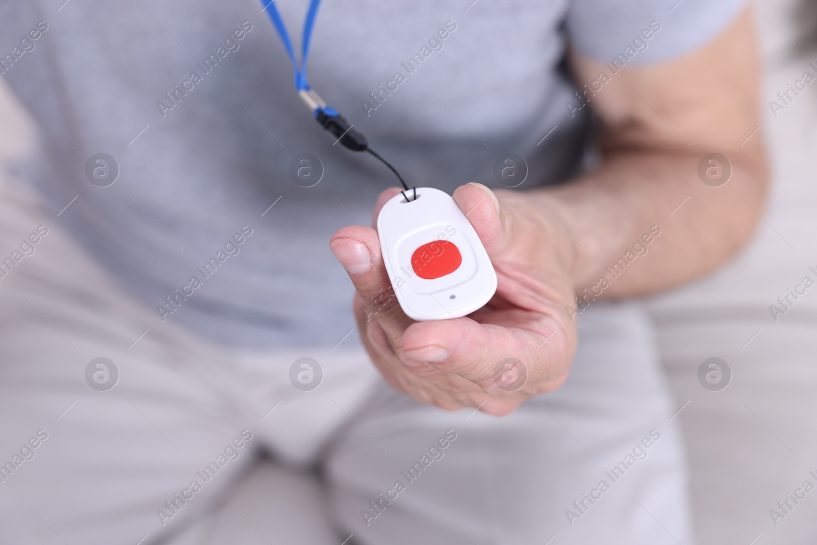 Photo of Senior man with emergency call button at home, closeup