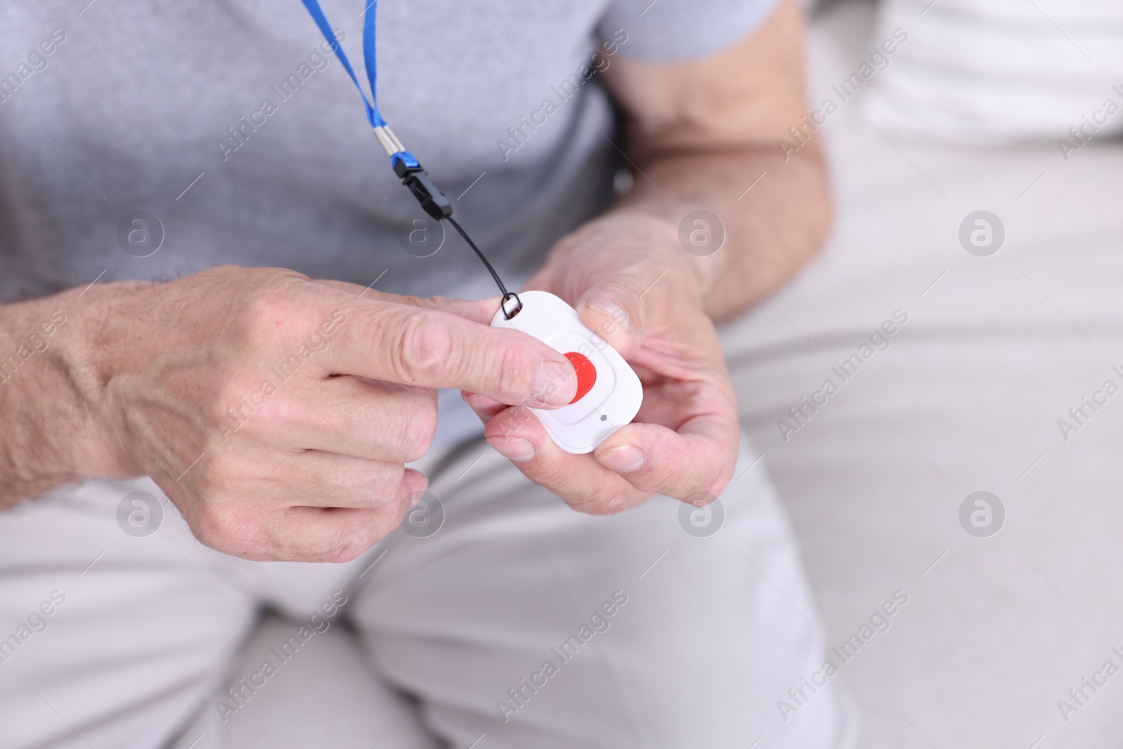 Photo of Senior man pressing emergency call button at home, closeup