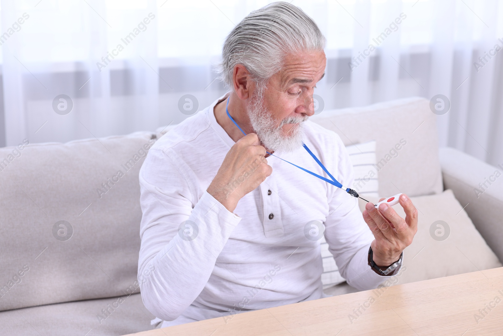 Photo of Senior man with emergency call button at home