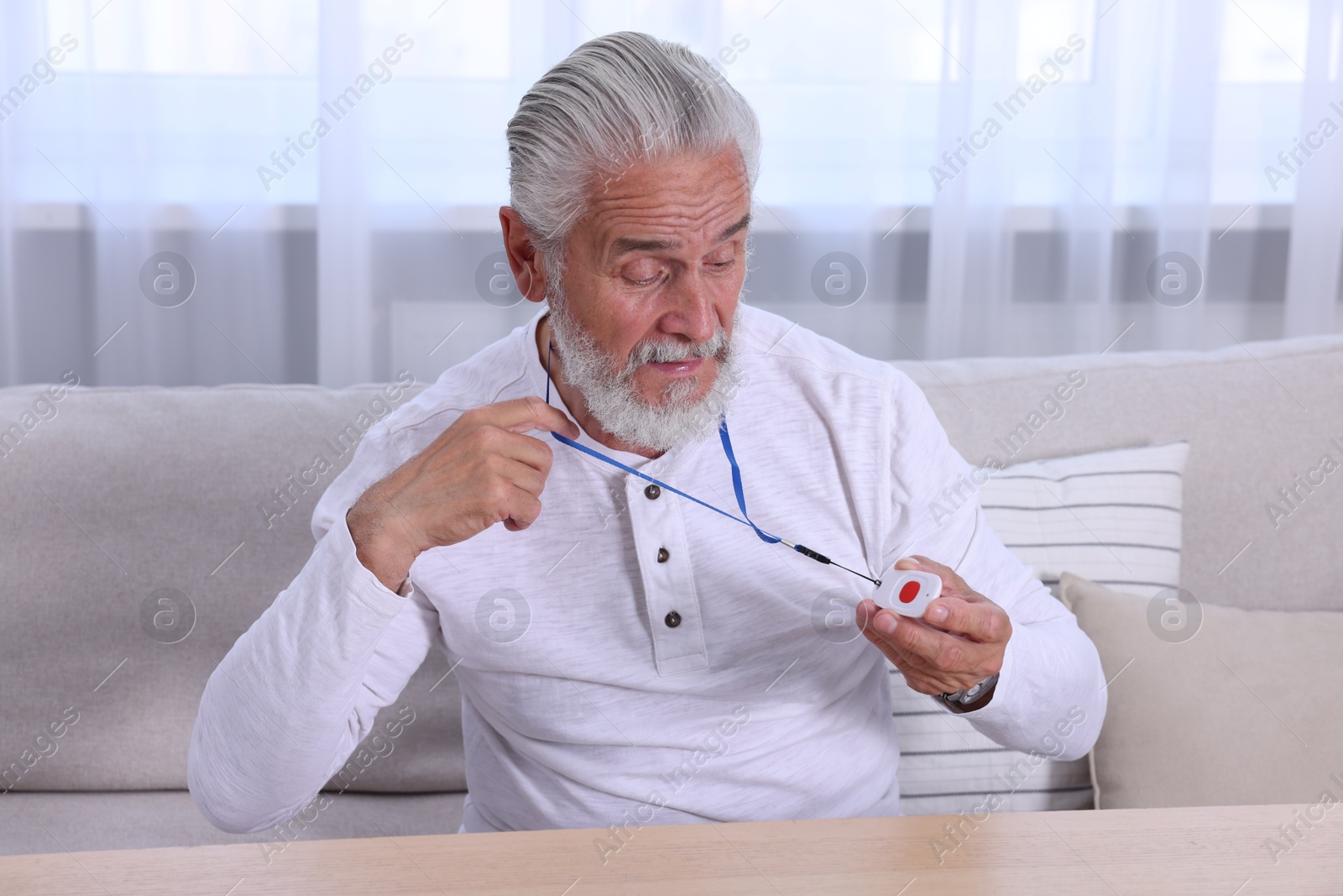 Photo of Senior man with emergency call button at home