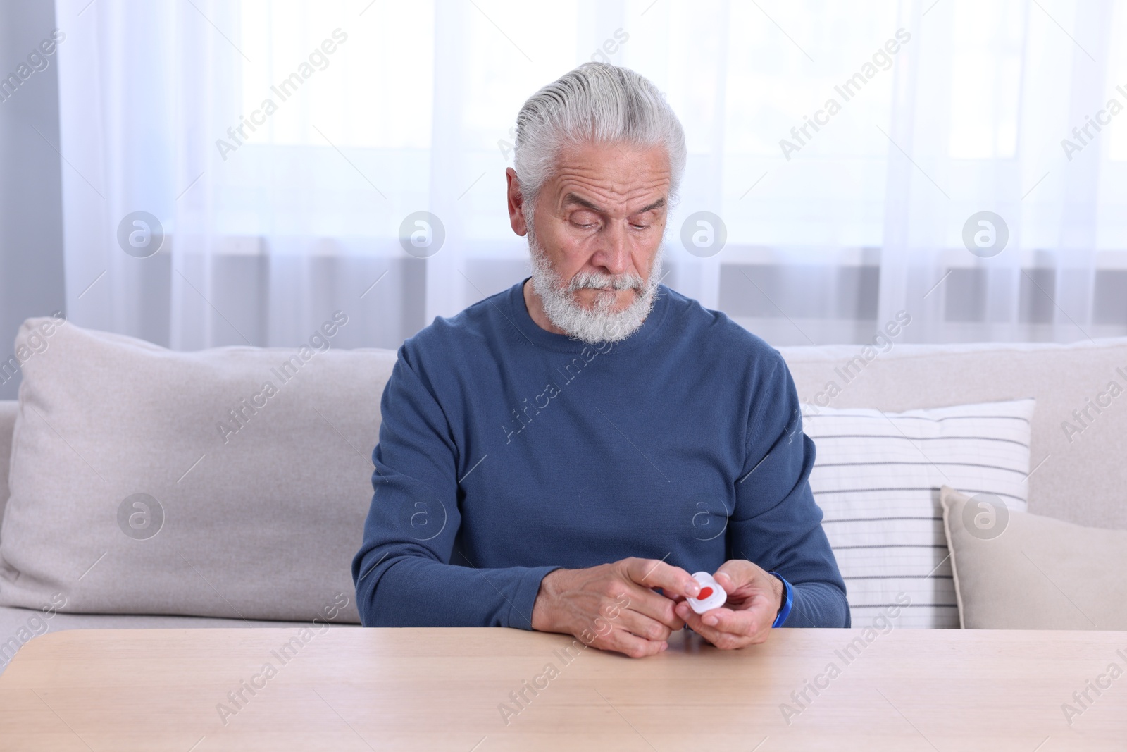 Photo of Senior man pressing emergency call button at home