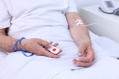 Photo of Senior man with emergency call button on bed in hospital, closeup