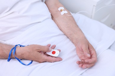 Photo of Senior man with emergency call button on bed in hospital, closeup