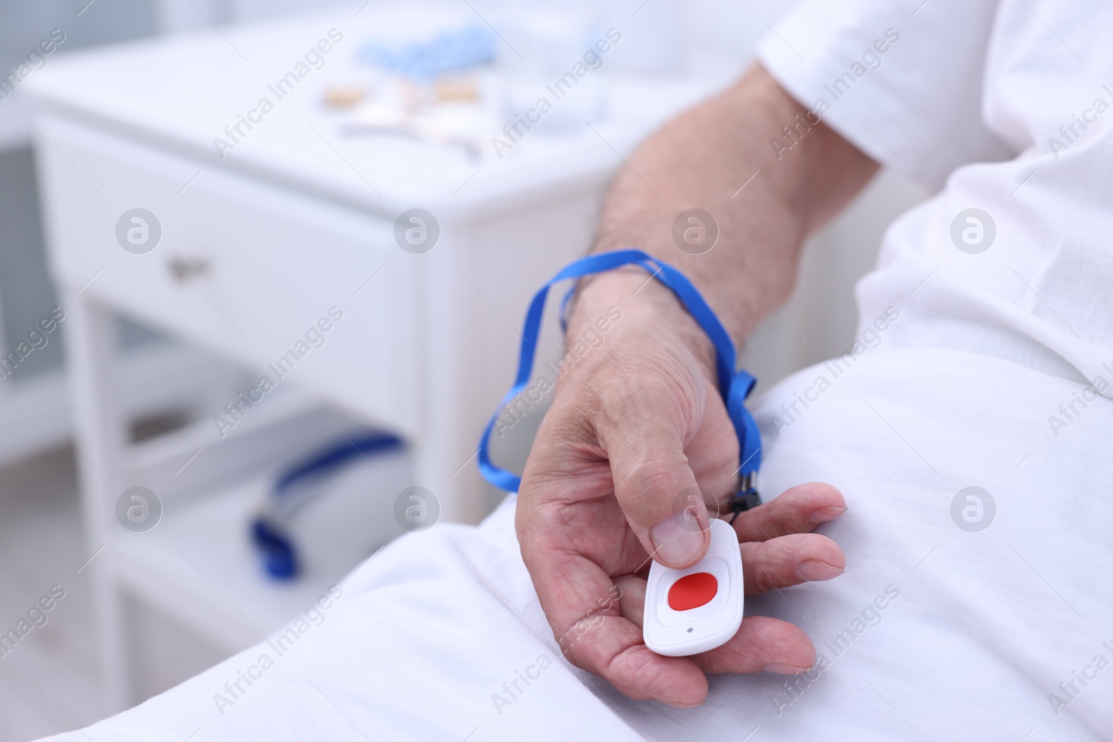 Photo of Senior man with emergency call button on bed in hospital, closeup