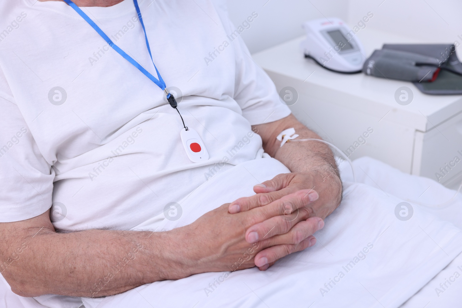 Photo of Senior man with emergency call button on bed in hospital, closeup