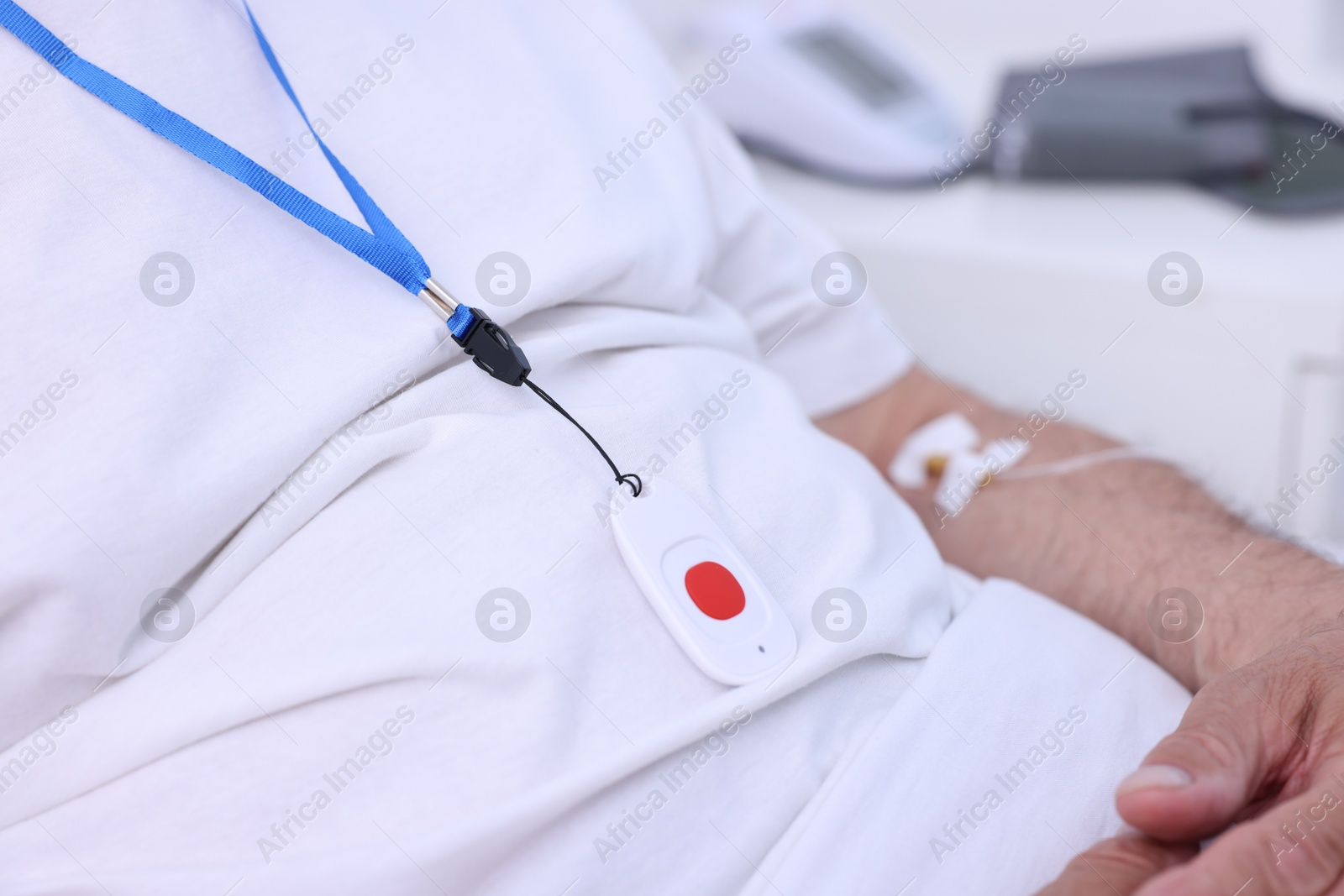 Photo of Senior man with emergency call button on bed in hospital, closeup