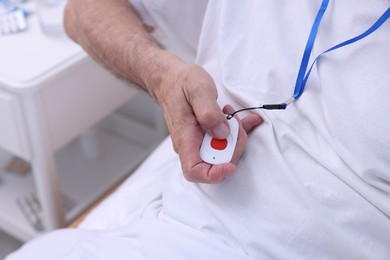 Photo of Senior man pressing emergency call button on bed in hospital, closeup