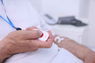 Senior man pressing emergency call button on bed in hospital, closeup