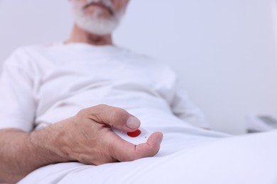 Photo of Senior man with emergency call button on bed in hospital, closeup