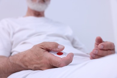 Senior man with emergency call button on bed in hospital, closeup