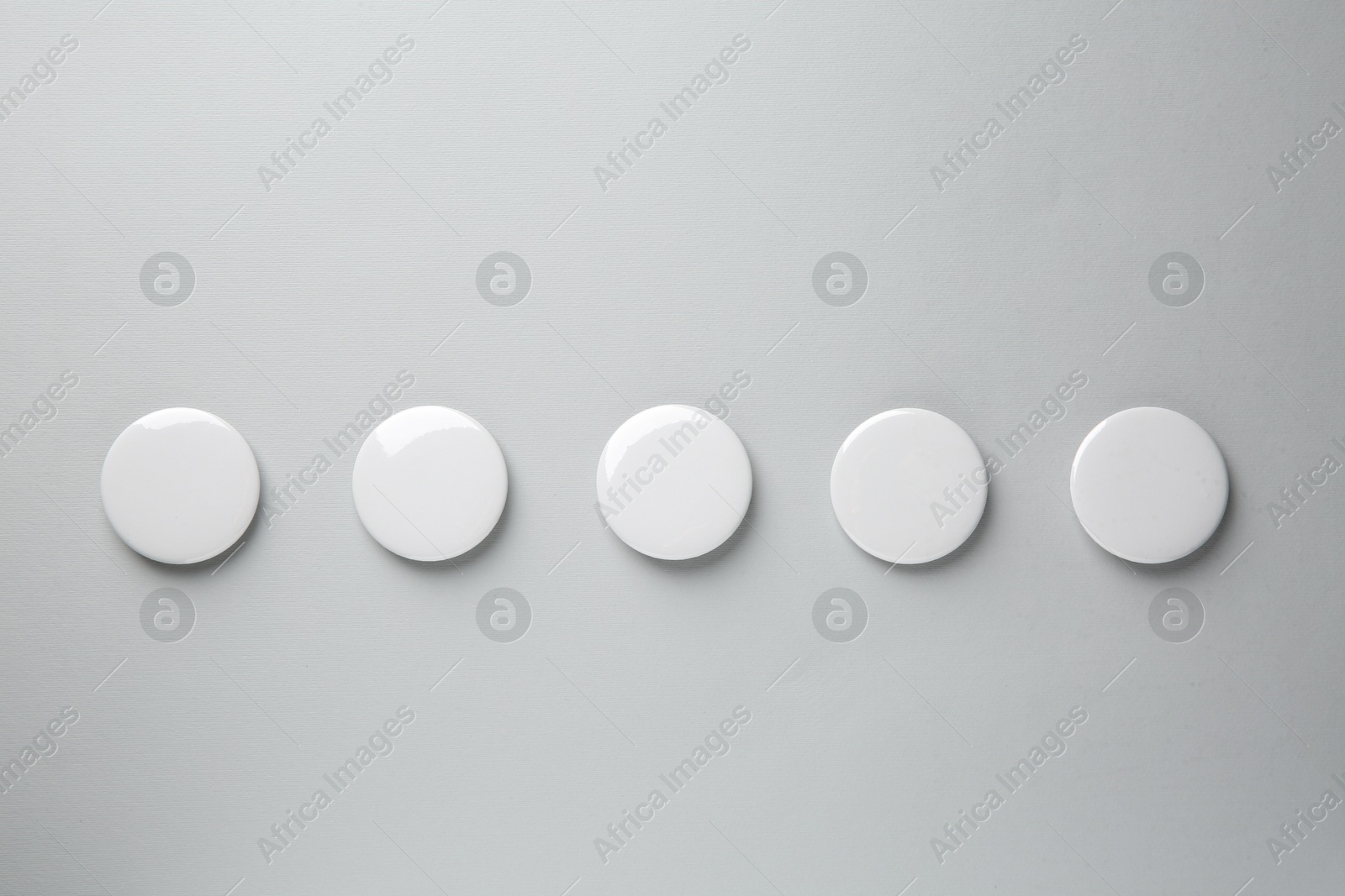 Photo of Blank white button badges on grey background, top view. Mockup for design