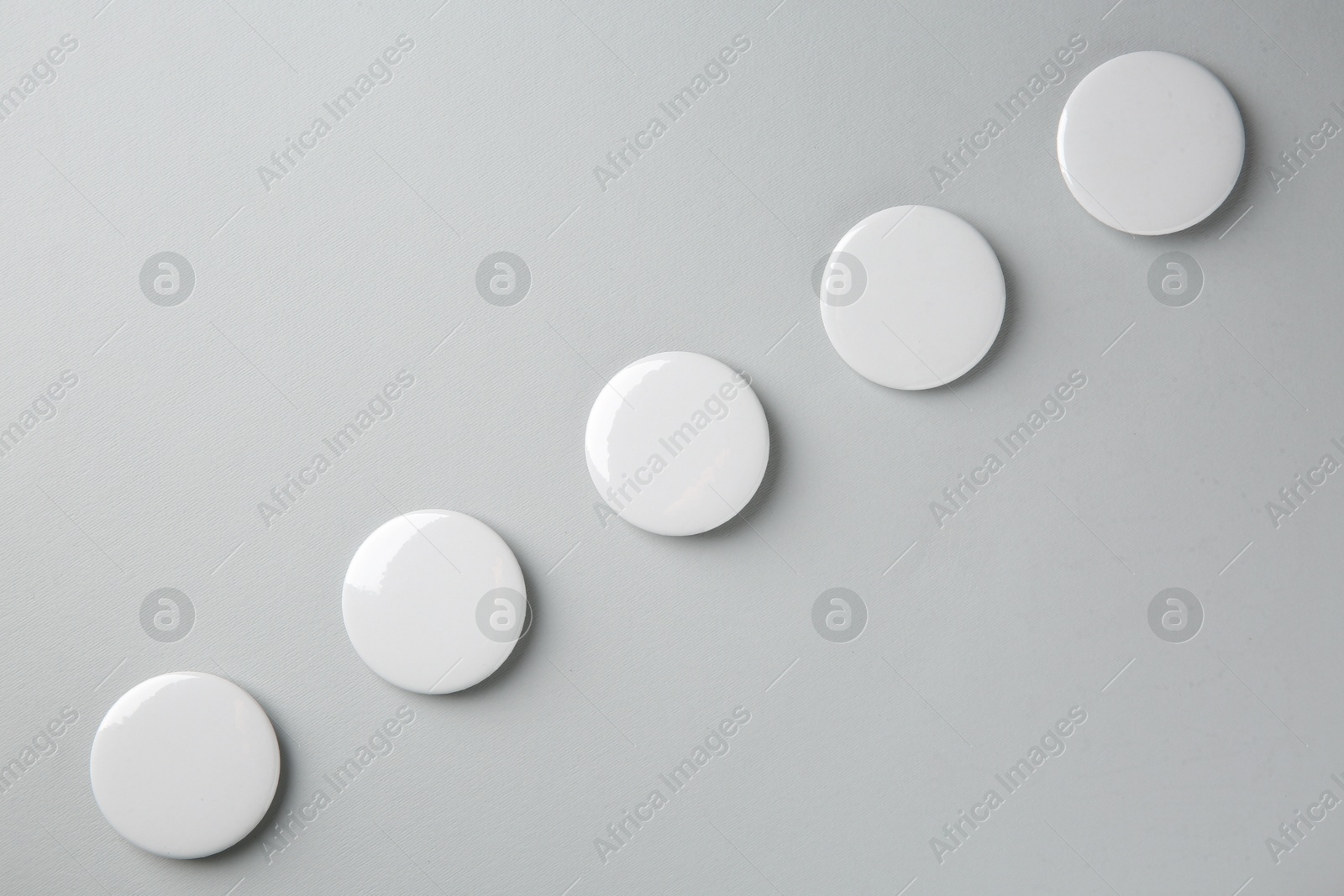 Photo of Blank white button badges on grey background, top view. Mockup for design