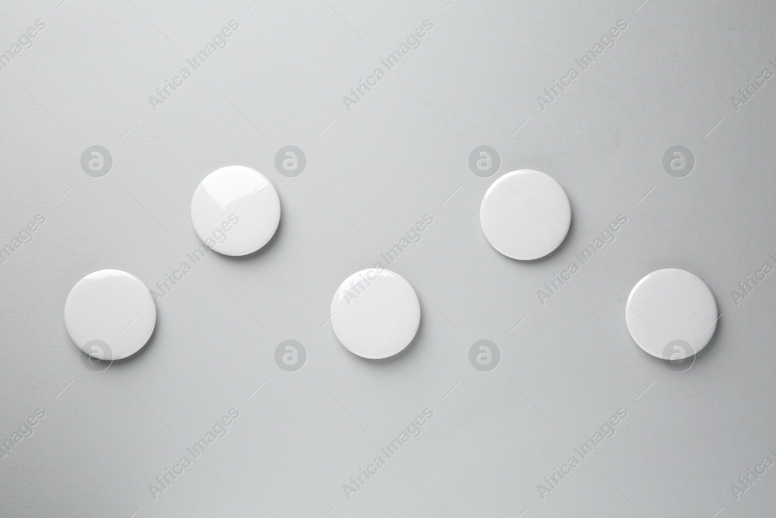 Photo of Blank white button badges on grey background, top view. Mockup for design