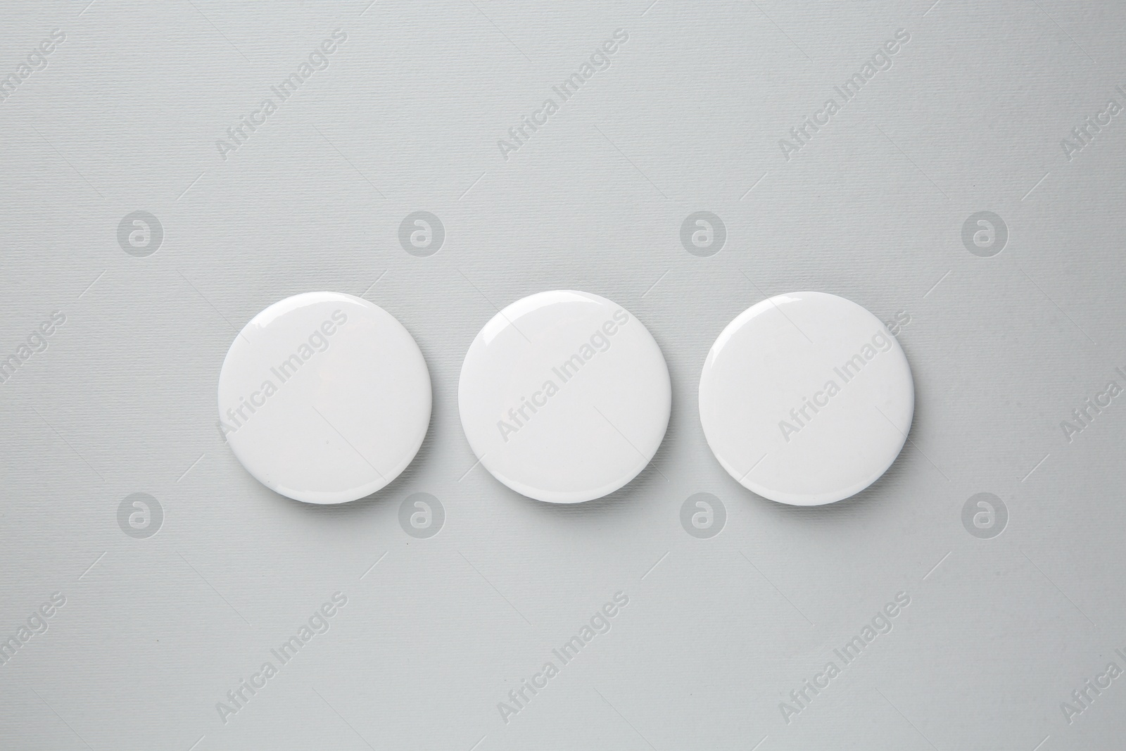 Photo of Blank white button badges on grey background, top view. Mockup for design