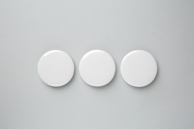 Blank white button badges on grey background, top view. Mockup for design