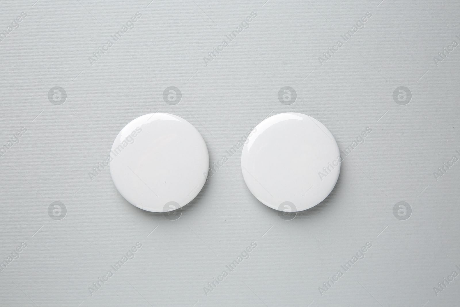 Photo of Blank white button badges on grey background, top view. Mockup for design