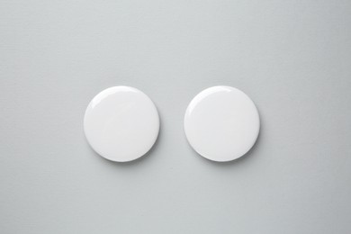 Photo of Blank white button badges on grey background, top view. Mockup for design