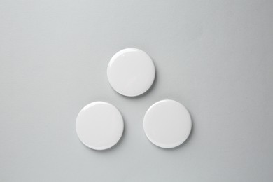 Blank white button badges on grey background, top view. Mockup for design