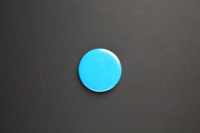 Photo of Blank light blue button badge on black background, top view. Mockup for design