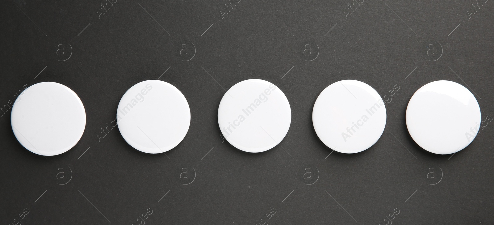 Photo of Blank white button badges on black background, top view. Mockup for design