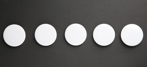 Photo of Blank white button badges on black background, top view. Mockup for design