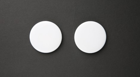 Photo of Blank white button badges on black background, top view. Mockup for design