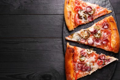 Photo of Board with pieces of delicious pizza Diablo on black wooden table, top view. Space for text