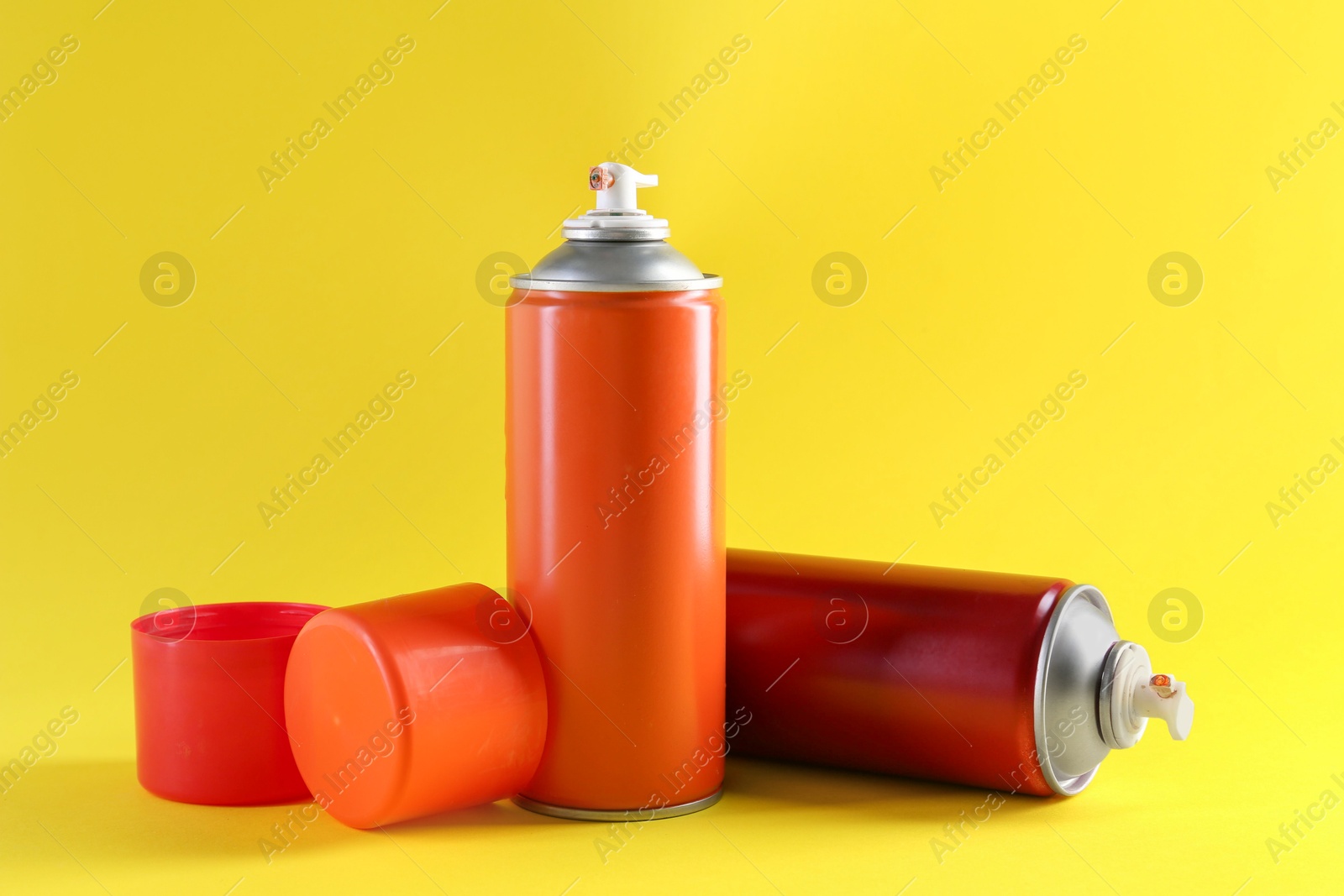 Photo of Two spray paint cans on yellow background