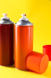 Photo of Two spray paint cans on yellow background