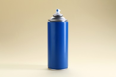 Photo of Blue spray paint can on beige background