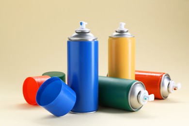 Photo of Many spray paint cans on beige background