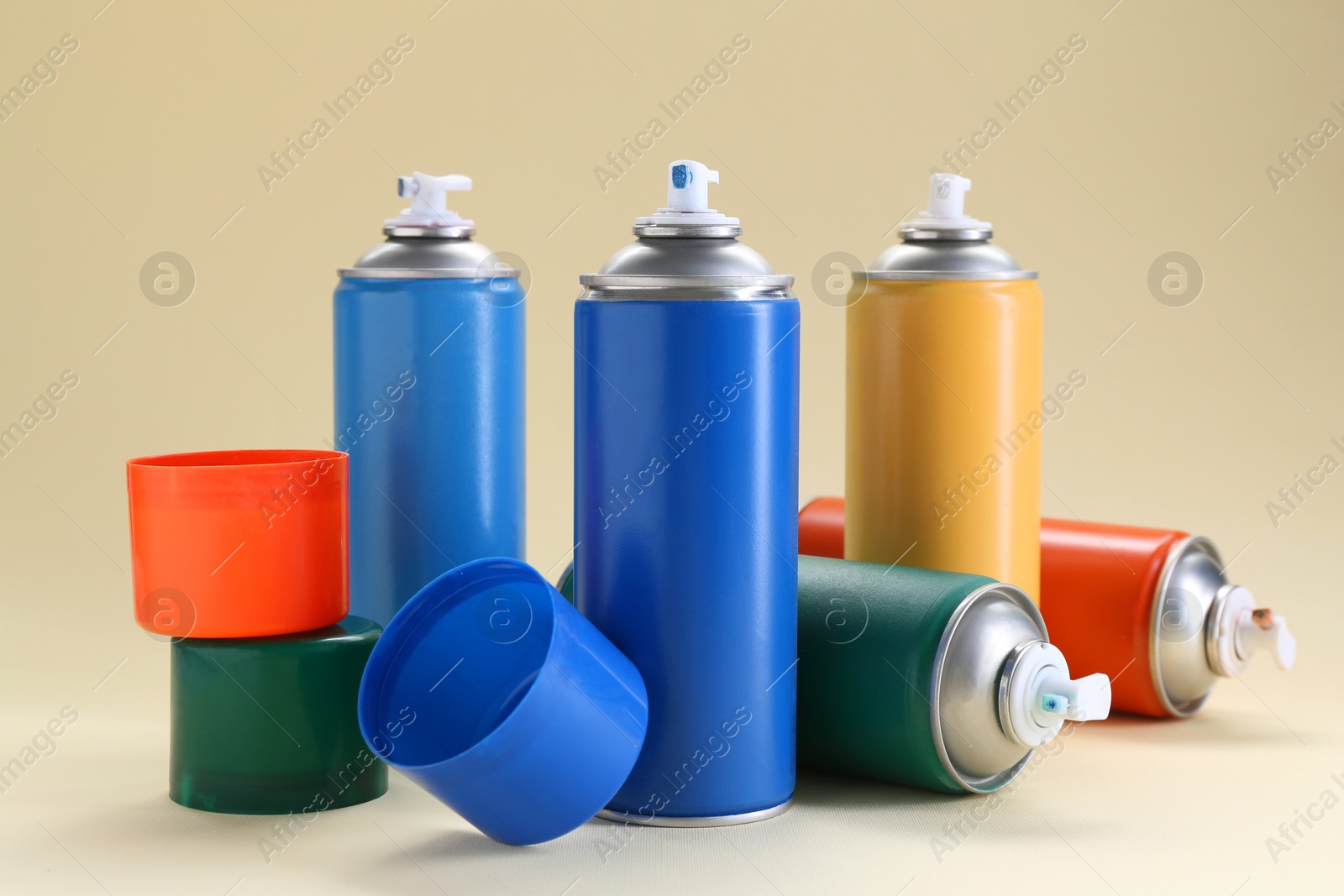 Photo of Many spray paint cans on beige background