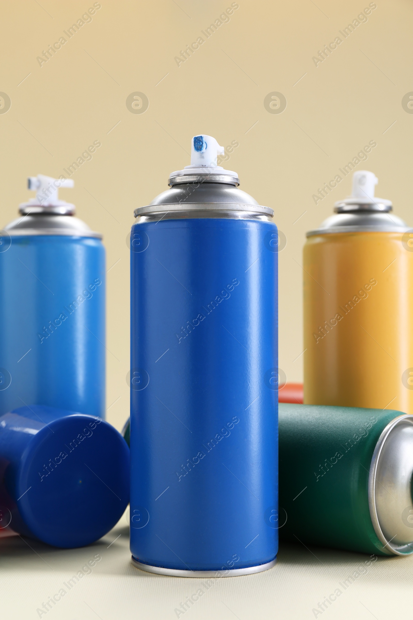 Photo of Many spray paint cans on beige background