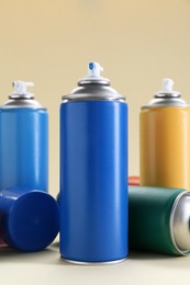 Many spray paint cans on beige background