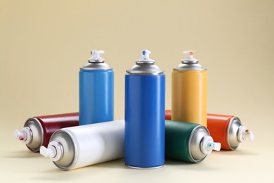 Photo of Many spray paint cans on beige background