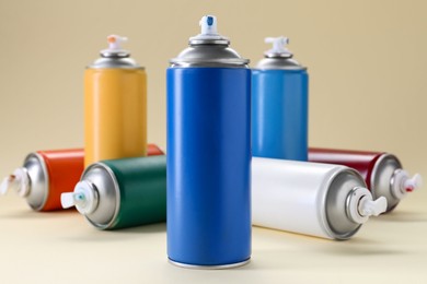 Photo of Many spray paint cans on beige background