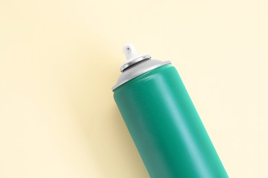 Green spray paint can on beige background, top view. Space for text