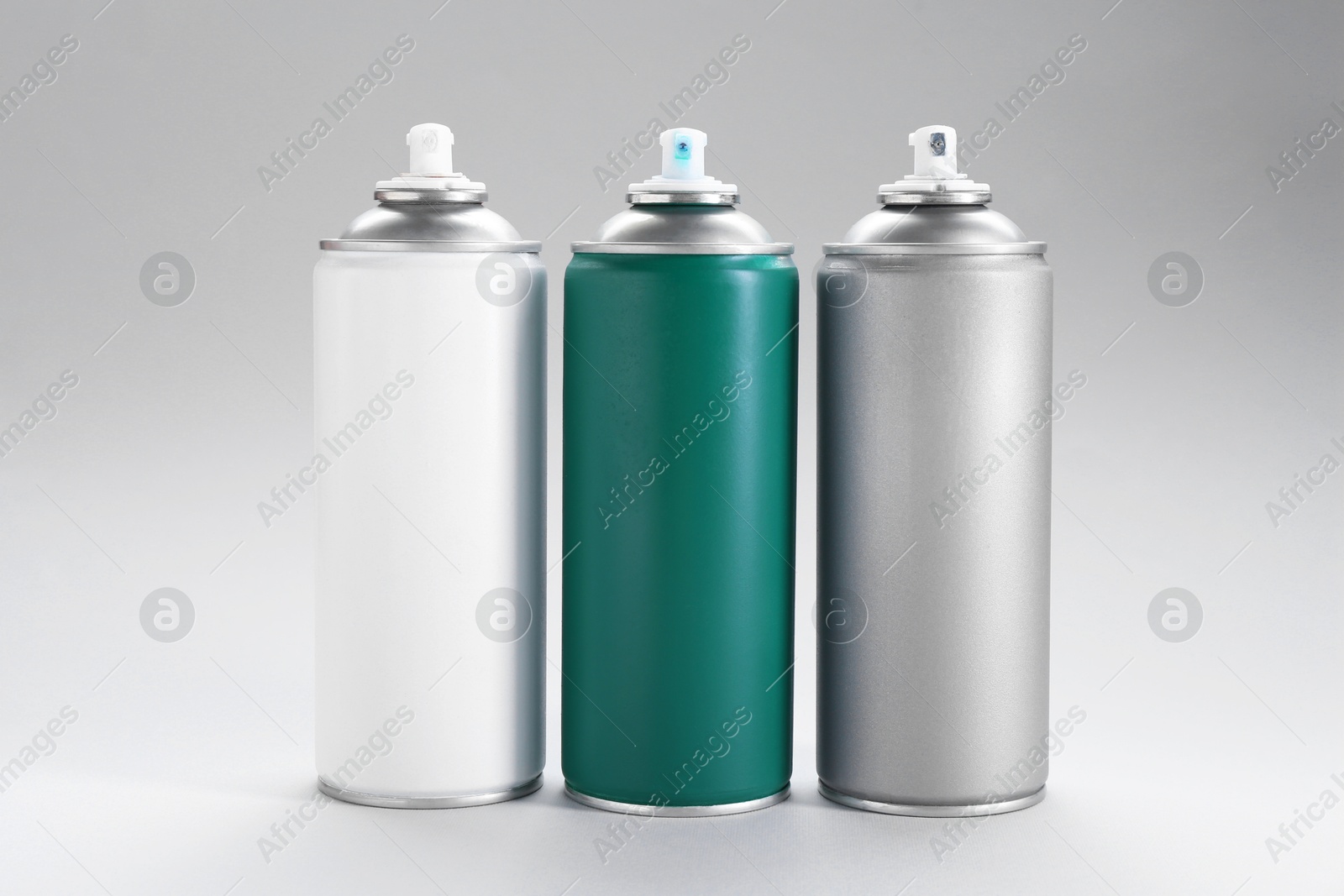 Photo of Three spray paint cans on gray background