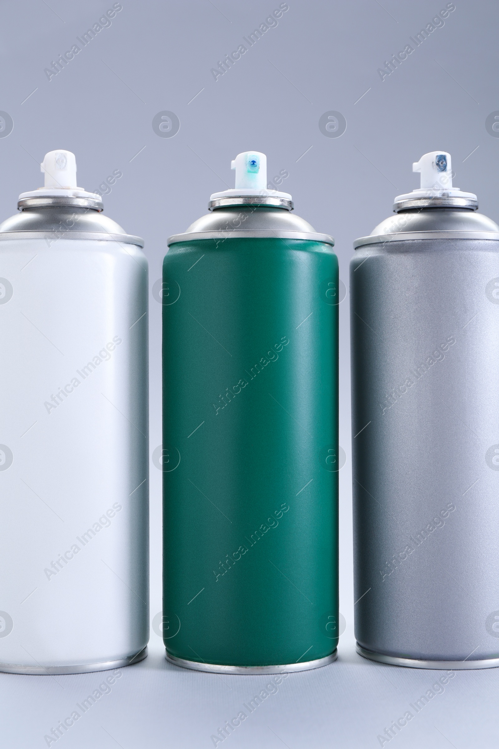 Photo of Three spray paint cans on gray background