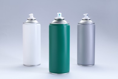 Photo of Three spray paint cans on gray background