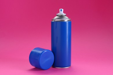 Blue spray paint can on pink background