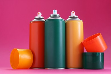 Photo of Many spray paint cans on pink background