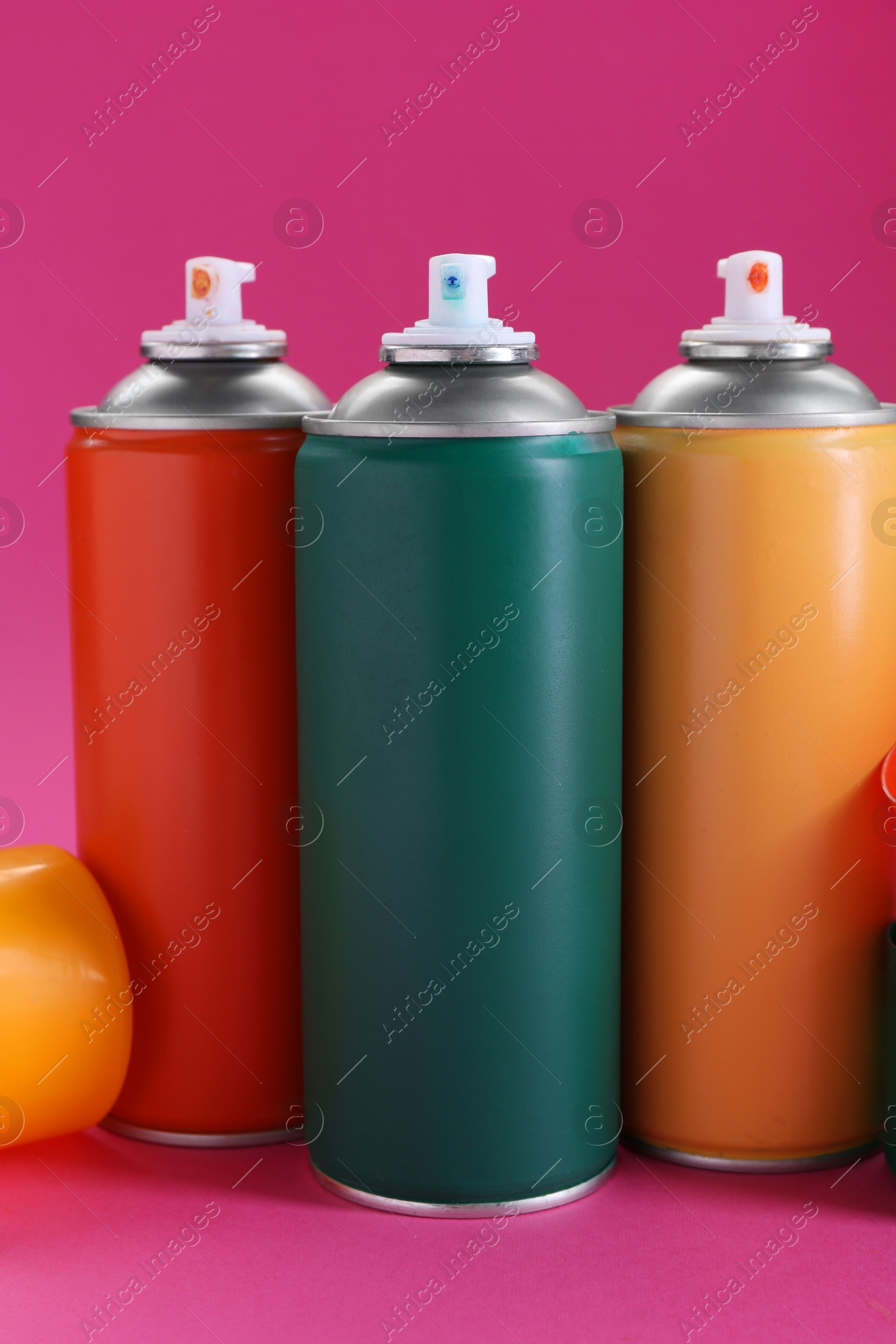 Photo of Many spray paint cans on pink background