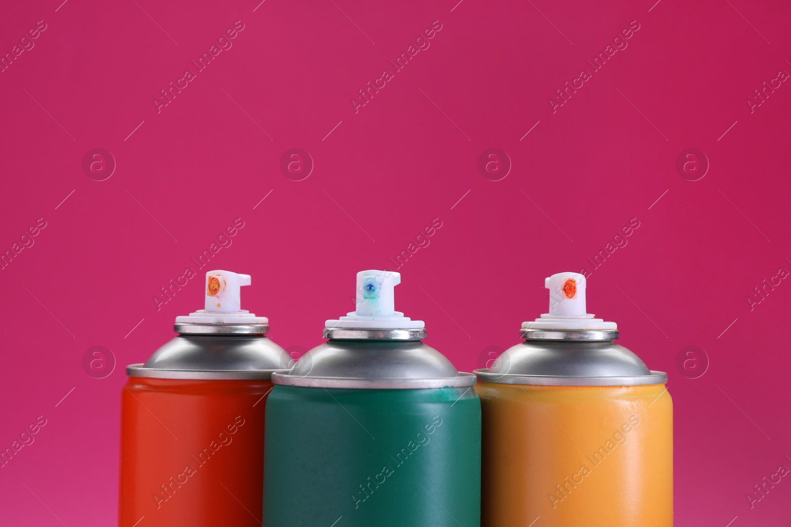 Photo of Many spray paint cans on pink background, closeup. Space for text